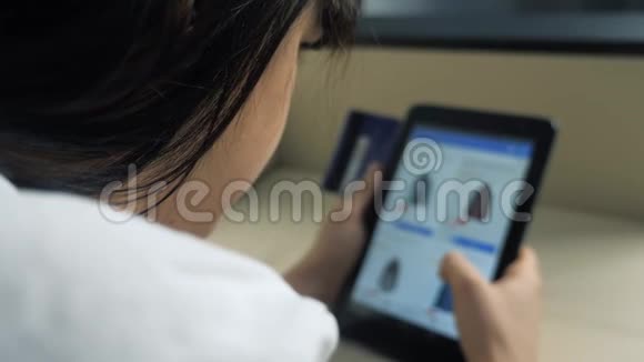 女孩用数字平板电脑制作网上购物概念布鲁内特躺在沙发上看着网上的生活方式视频的预览图
