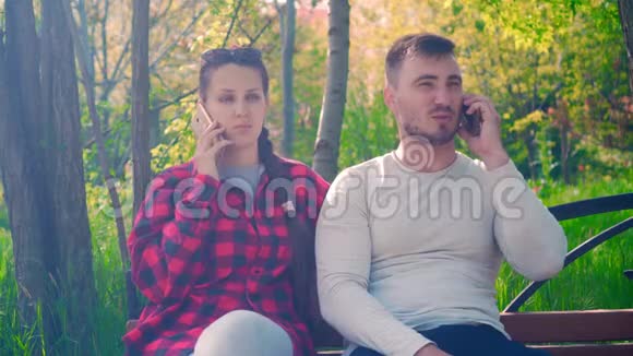年轻夫妇在电话智能手机上聊天一个穿黑色和红色衬衫的女孩一个穿灰色T恤的男人视频的预览图