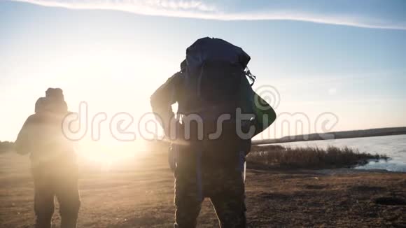 两名游客一起背着背包慢动作行走在阳光下剪影阳光照耀着生活方式视频的预览图