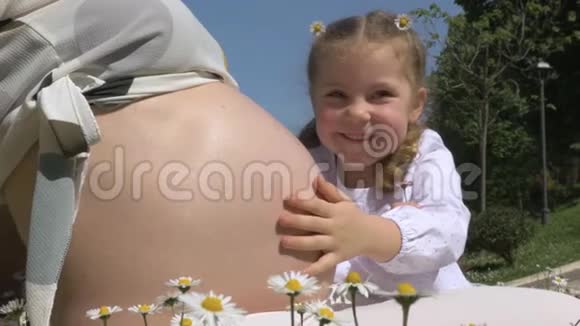 可爱的小女孩拥抱妈妈怀孕的肚子视频的预览图