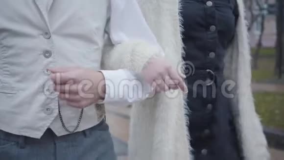 男女白种人手的特写男朋友和女朋友手挽手走路穿白色衬衫和背心的男人视频的预览图