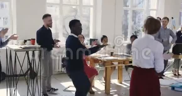 快乐千禧黑人商人做疯狂的庆祝舞蹈同事祝贺老板在健康的工作场所视频的预览图