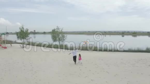 镜头的跨度越过海滩上面跑着一个孙女祖父手里拿着风筝4K慢视频的预览图