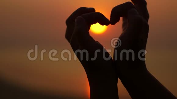 在日落的背景上用手指做心脏的手势视频的预览图
