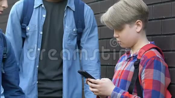 十几岁的青少年抢着年轻男孩的智能手机羞辱受害者问题视频的预览图