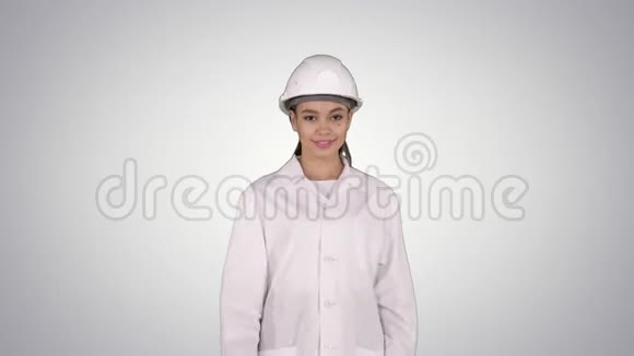 成熟的女工程师戴着安全帽用手指着产品或文字在渐变背景下行走视频的预览图