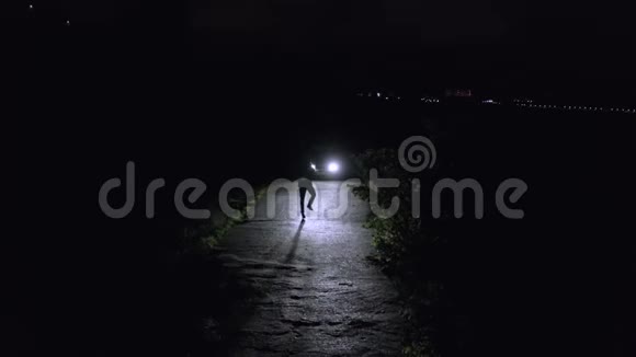 年轻人在黑暗的道路上跳舞在黑暗的道路上点燃前灯在黑暗的道路上跳跃的人照亮了c视频的预览图