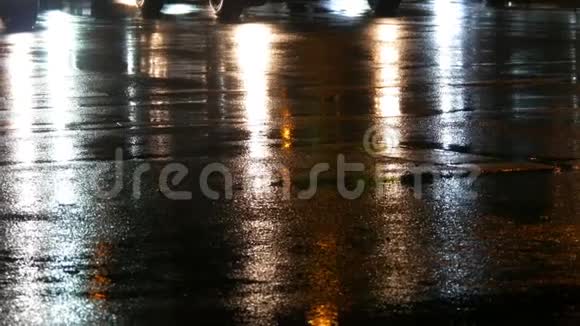汽车在交通前灯在雨中的沥青视图下面晚上雨打水坑汽车灯光的反射视频的预览图