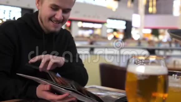 一个留胡子的年轻人在餐馆里看菜单视频的预览图