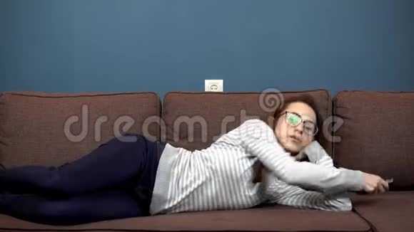 一个戴眼镜的年轻女人看电视躺在沙发上的女孩视频的预览图
