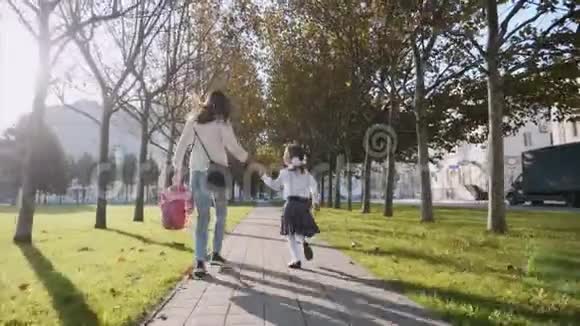 一个穿着校服的女人和小女孩跑在公园steadam后景视频的预览图
