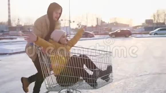 快乐的年轻朋友骑着手推车在商场停车阳光照在背景上慢动作视频的预览图