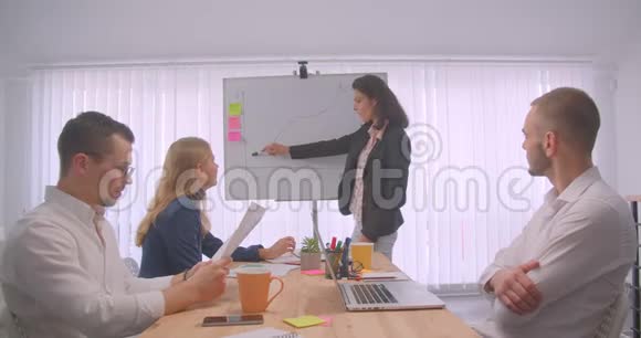 四个欢快的拼贴画在办公室室内开会女商人在白板上画一张图表视频的预览图