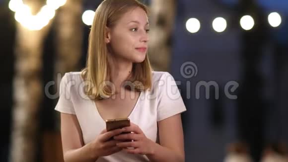 女人在晚上使用智能手机坐在咖啡店里视频的预览图
