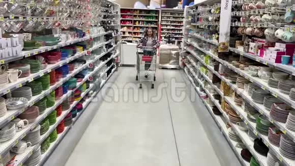 积极的年轻女人在超市里玩得很开心那个女孩骑着手推车4K慢慢视频的预览图