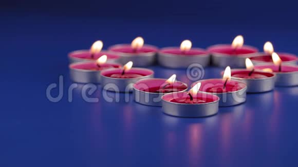 12支粉红色香味的蜡烛放在蓝色背景的铁烛台上视频的预览图