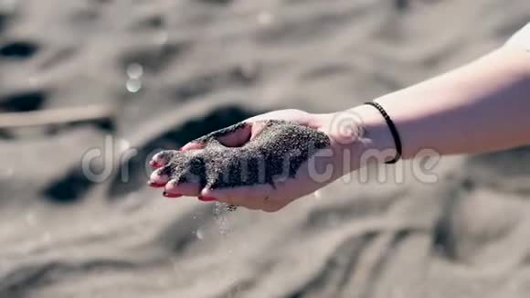 女人罗马地中海海滩上黑色火山沙的手视频的预览图