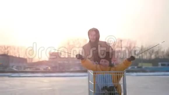 一对幸福的年轻夫妇在购物中心停车场的手推车上骑着火花车阳光照在背景上慢动作视频的预览图