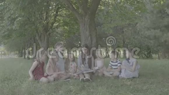 Vlog女青年作为教育家在公园为男孩和女孩读书视频的预览图