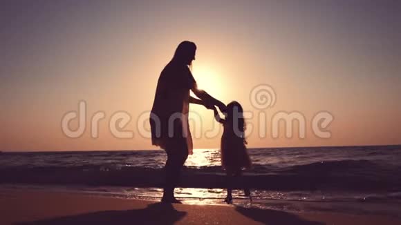 幸福的家庭和海上日出妈妈和小女孩在海滩上跳舞视频的预览图