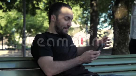 男人在公园里使用智能手机好像没人偷窥他的手机视频的预览图