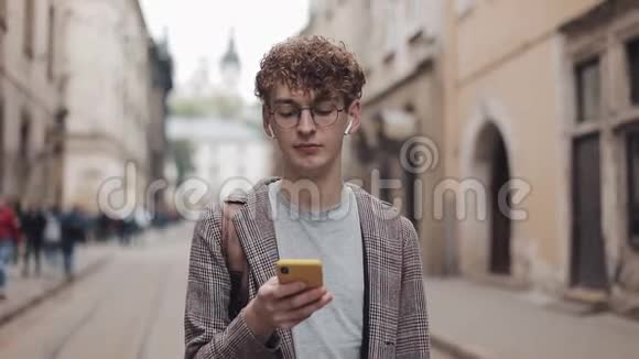 戴着夹克拿着智能手机看着屏幕而不是照相机的年轻男人的肖像视频的预览图