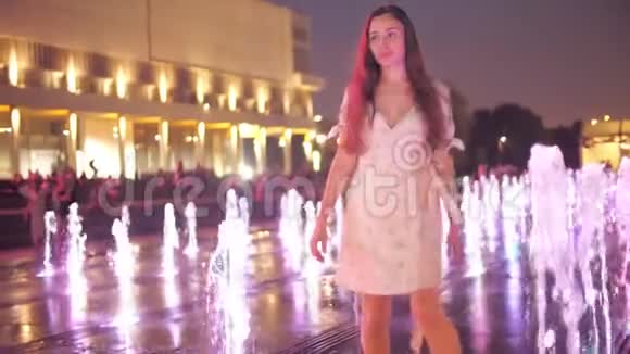 晚上美丽的年轻女子在明亮的喷泉里跳舞动作缓慢视频的预览图