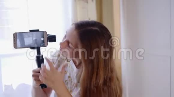 一个年轻快乐的女孩笑着用手机与朋友在线视频聊天并在社交媒体上博客视频的预览图