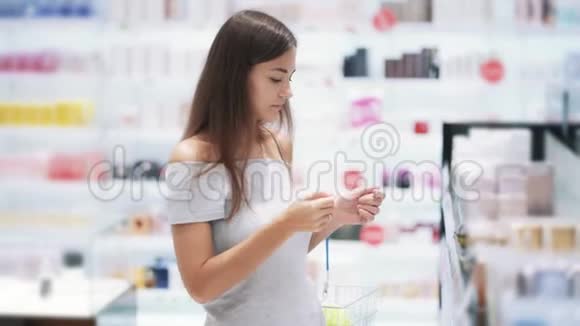 女孩在化妆品店选择香水闻一闻放进篮子慢动作视频的预览图