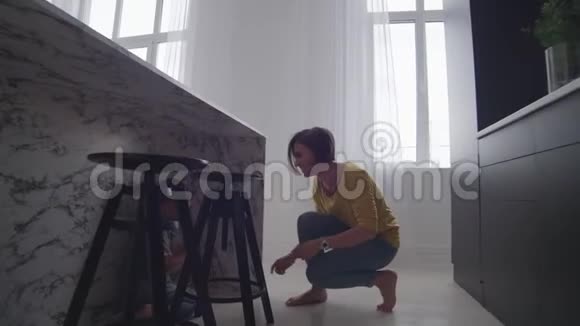 快乐的妈妈和一个孩子在一个明亮的公寓里玩追赶笑着绕着房子跑视频的预览图