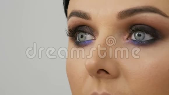 化妆师用特殊的画笔丁香花和珍珠般的烟熏眼影眼睛和眼影制作出烟熏眼模特视频的预览图