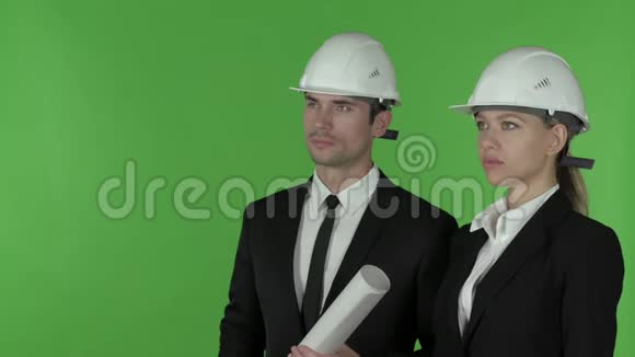 女建筑工程师的正面视线指向站着的男工程师拿着蓝图色度键视频的预览图
