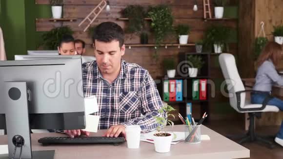 自信的商人在电脑上打字享受一杯咖啡视频的预览图