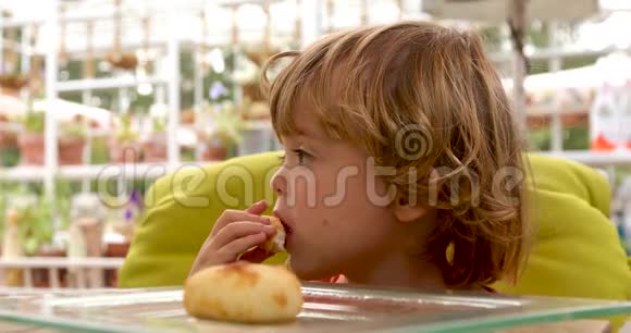 体贴的孩子在咖啡馆的餐桌上吃面包视频的预览图