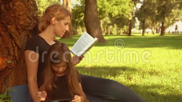 妈妈和孩子在公园里看书和玩耍视频的预览图