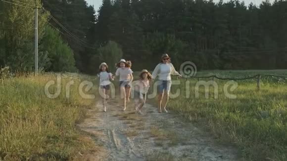 快乐的母亲和三个女儿沿着乡间小路奔跑视频的预览图