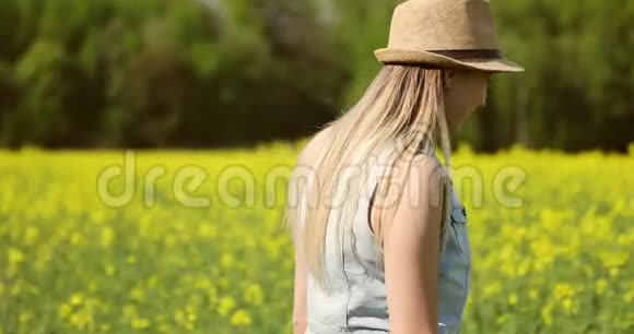 美丽的女人在夏天走在一个大油菜田里视频的预览图