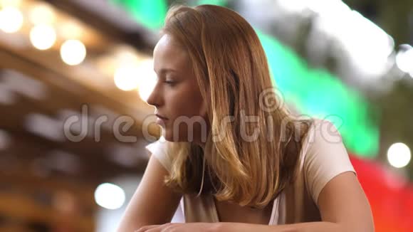 金发女孩听有人坐在户外咖啡馆里视频的预览图