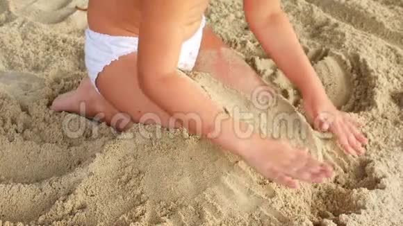 无法辨认的孩子把双脚埋在沙滩上视频的预览图