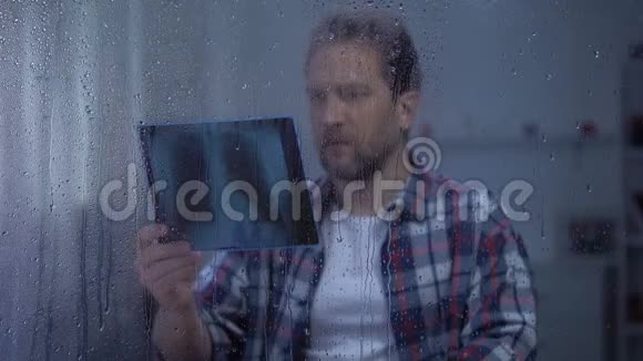 沮丧的男人在雨天看肺x光不治之症癌症视频的预览图