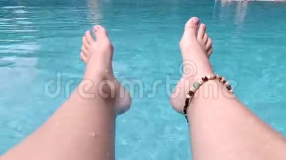 泳池中女性优雅的双腿特写女孩在晴天在热带游泳池放松视频的预览图