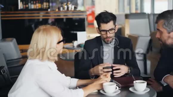 现代咖啡馆里与男性和女性伴侣交谈的胡子商人视频的预览图