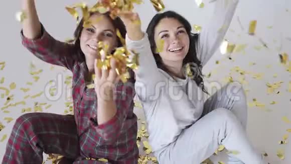 美丽的快乐女孩在白色背景上扔金色的五彩纸屑视频的预览图