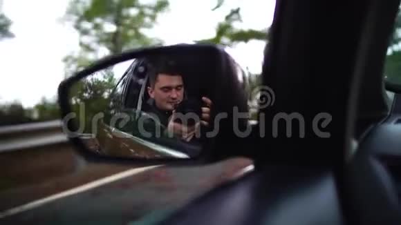 在早晨的旅途中带着相机的人在车镜中反射着一辆移动的汽车沿着秋天的雾路行驶慢动作视频的预览图