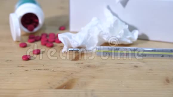 一个温度计躺在桌子上里面放着药丸和皱巴巴的东西视频的预览图