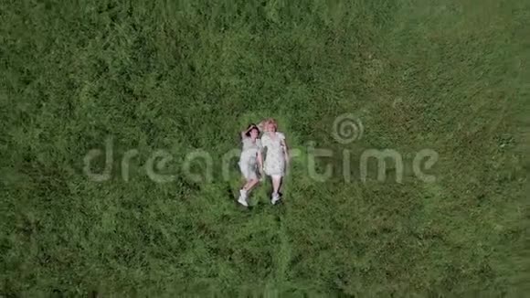 空中射击史诗般的视角从顶部对两个年轻的女人躺在草地上视频的预览图