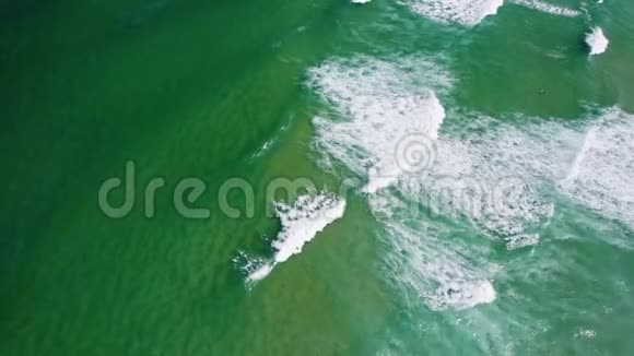 海浪向海岸滚动的顶部鸟瞰图鸟眼望翠绿色的海洋水面视频的预览图