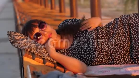 日落时分在海滩上休息的女人视频的预览图
