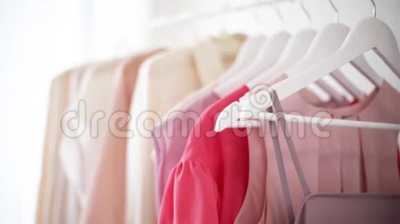 白色衣架上穿粉色米色和奶油色的女式服装视频的预览图