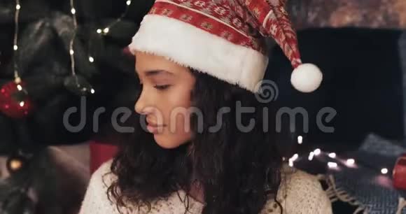 圣诞老人的迷人快乐女人有视频通话展示礼物盒到相机微笑着坐在附近视频的预览图